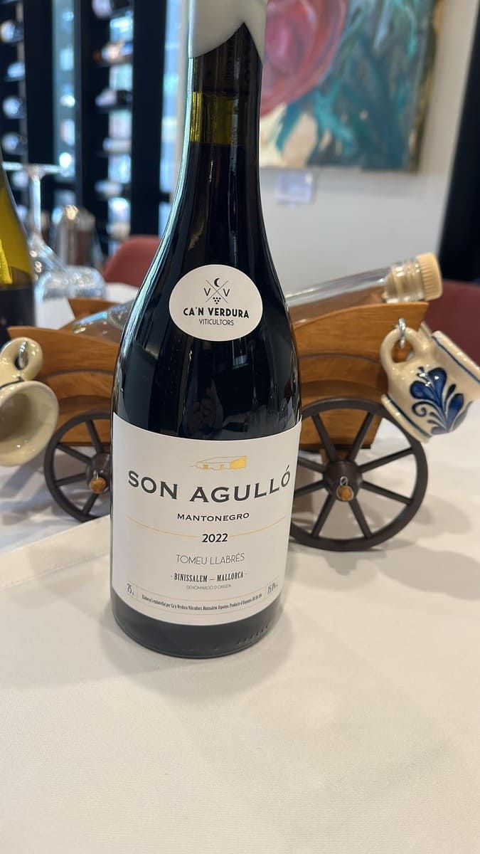 Una botella de vino son aguillo reposa sobre una mesa al lado de un carro de madera.