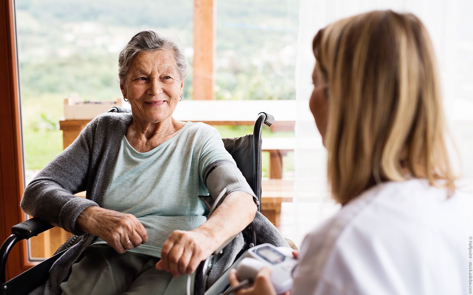 Eine ältere Frau im Rollstuhl spricht mit einer Krankenschwester.