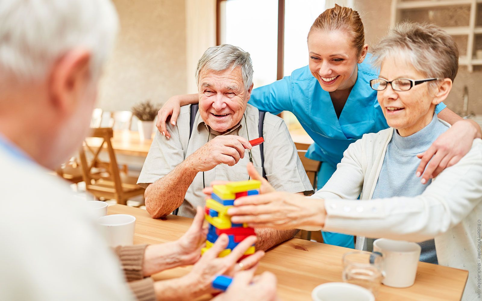 Eine Gruppe älterer Menschen spielt ein Spiel mit einer Krankenschwester.