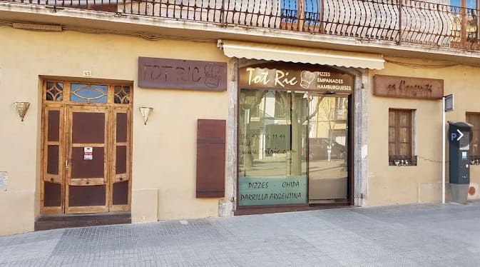 Street view of a small storefront with a glass door, wooden doors, and signs above the entrance.