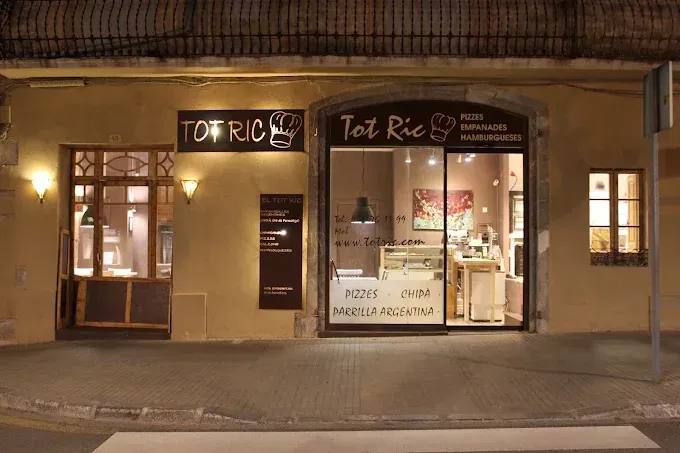 Street view of a small storefront with a glass door, wooden doors, and signs above the entrance.