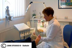 Regina Janßen untersucht in einem Bahndlungszimmer den Fuß eines Patienten.
