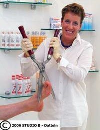 Regina Janßen hält eine Heckenschere über einen Fuß.