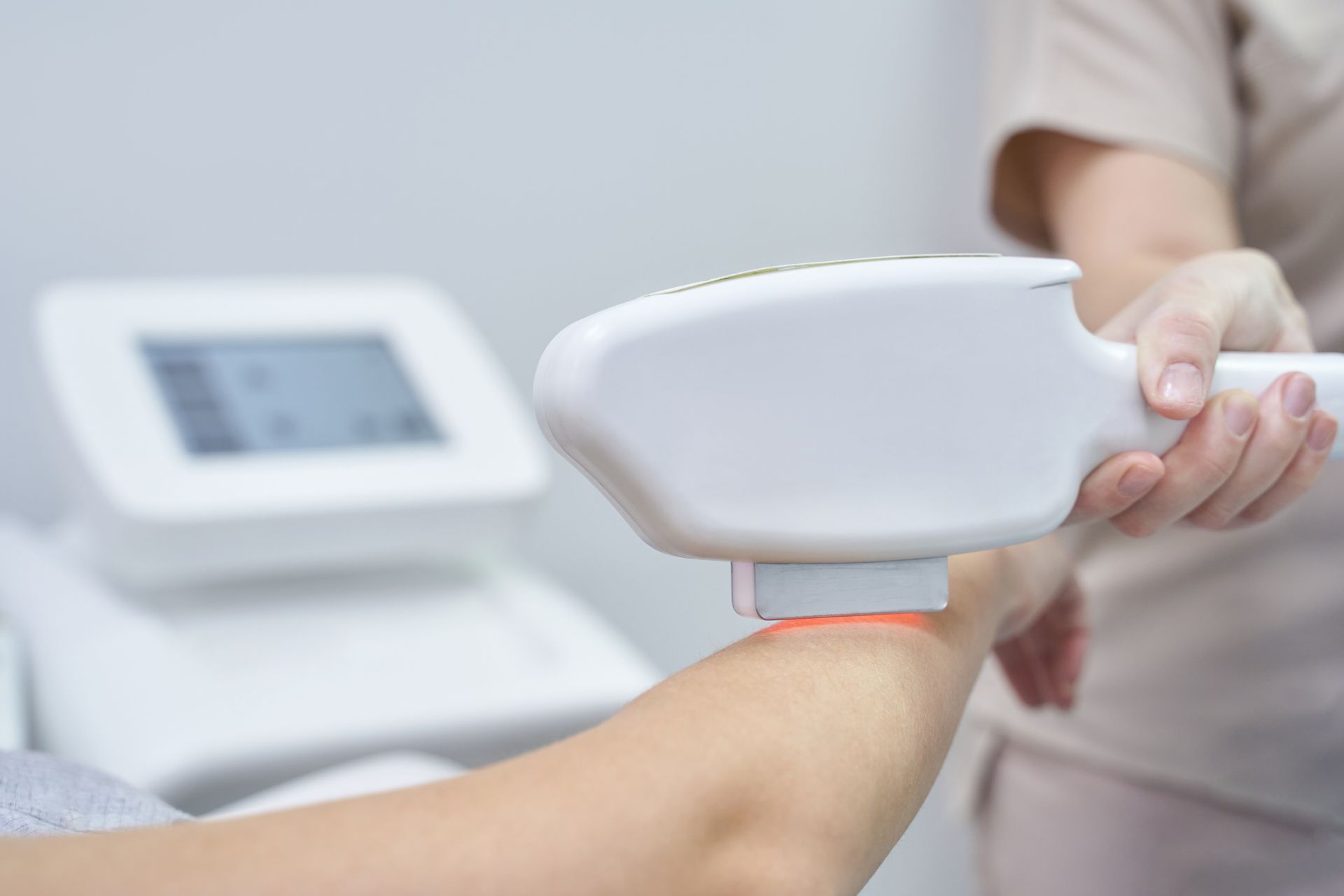 Der Arm einer Person wird in einer Klinik mit einem Laser-Haarentfernungsgerät behandelt.
