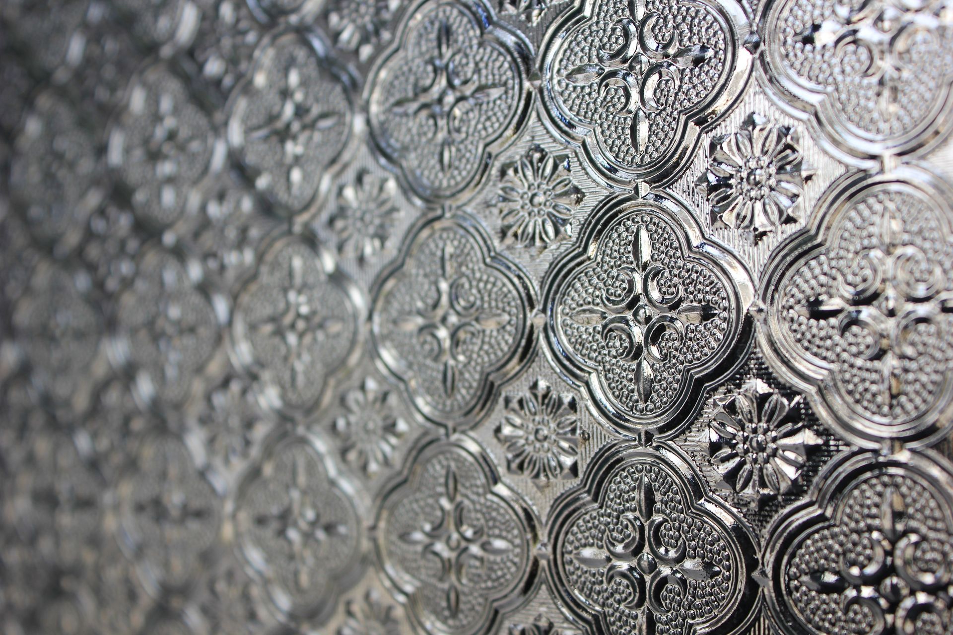 Strukturierte, klare Glasplatte mit einem sich wiederholenden floralen und geometrischen Muster.