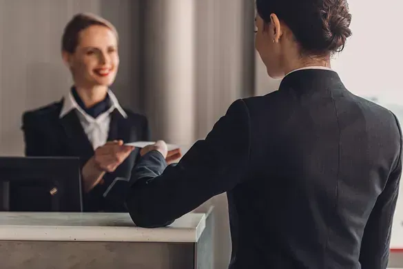 Una mujer le está dando una tarjeta de crédito a una recepcionista en un hotel.