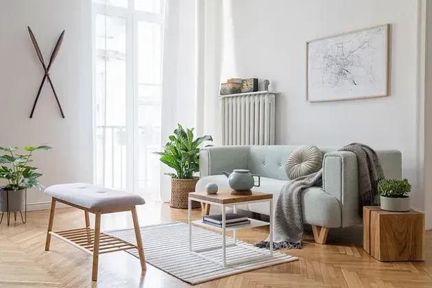 Una sala de estar con sofá, mesa, banco y plantas.