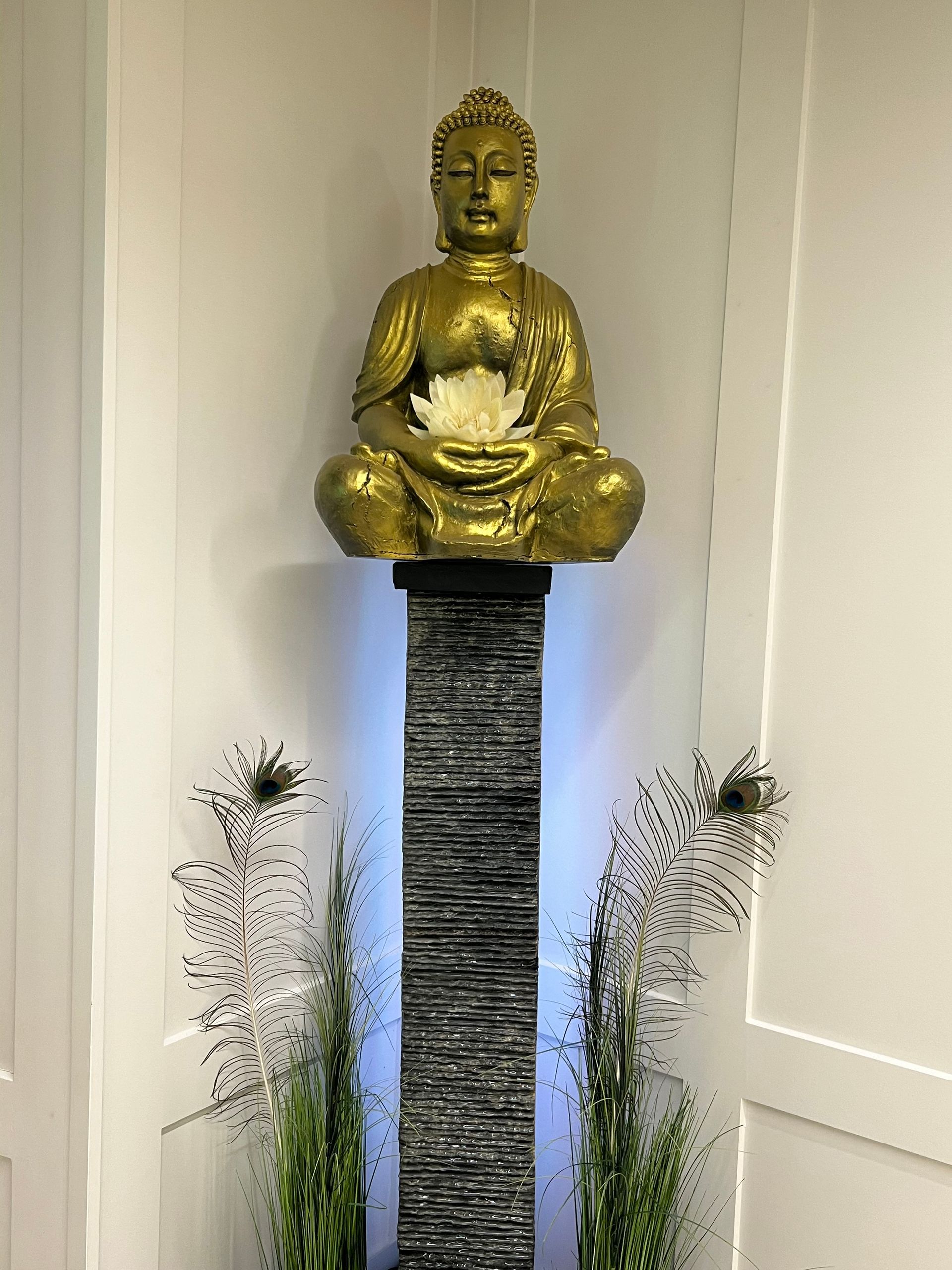 Ein Balipura-Armband liegt auf einem Blatt neben einer Statue.