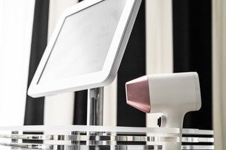 Auf einem Tisch neben einem Monitor steht ein Gerät zur Laser-Haarentfernung.