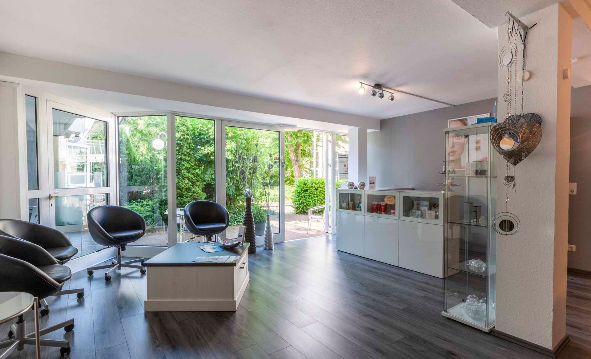 Eingangsbereich in der Beauty & Wellness Lounge mit Stühlen , einem Tisch und einer Glasvitrine .