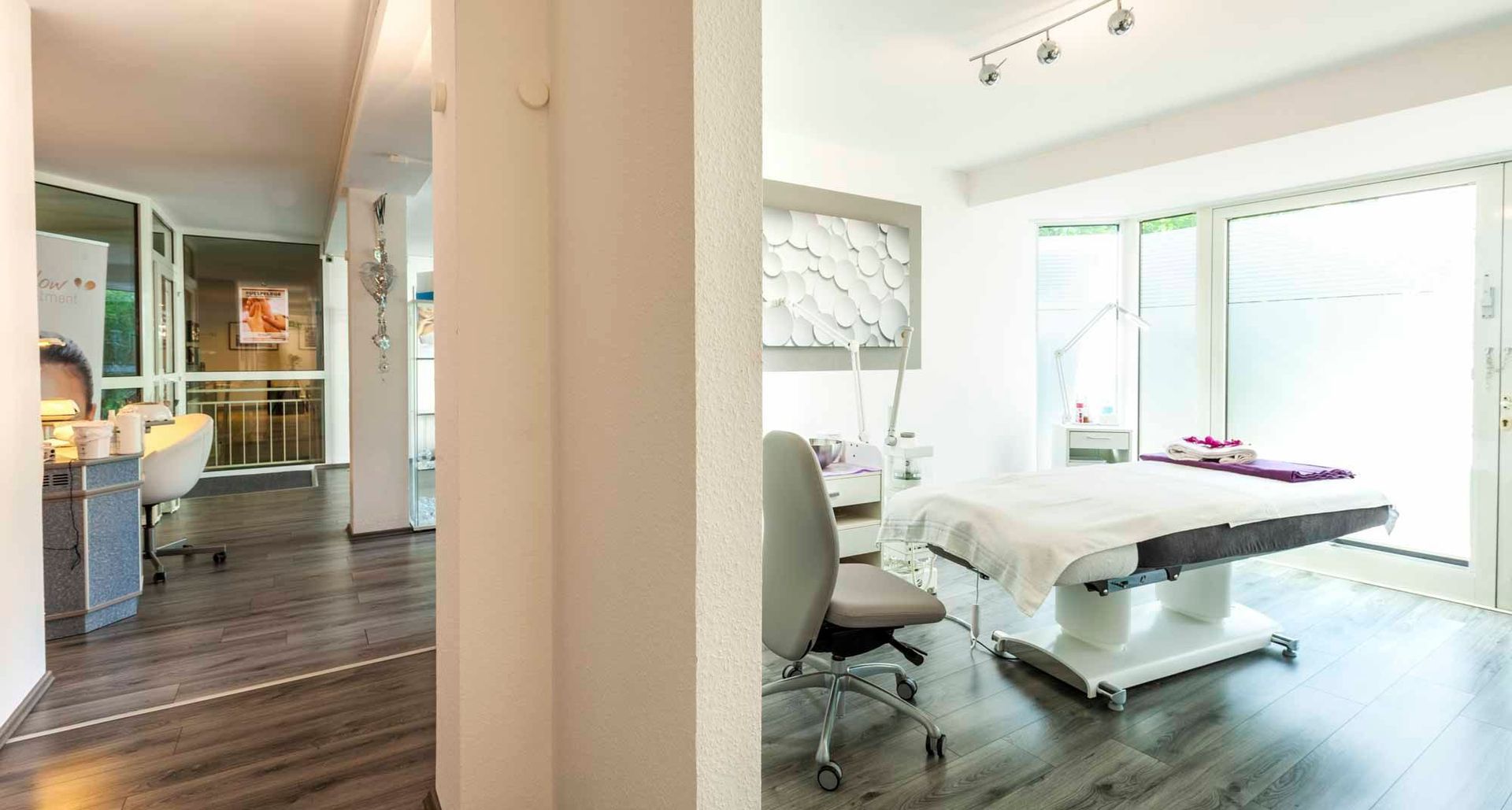 ein Raum in der Beauty & Wellness Lounge mit einem Massagetisch und einem Stuhl .