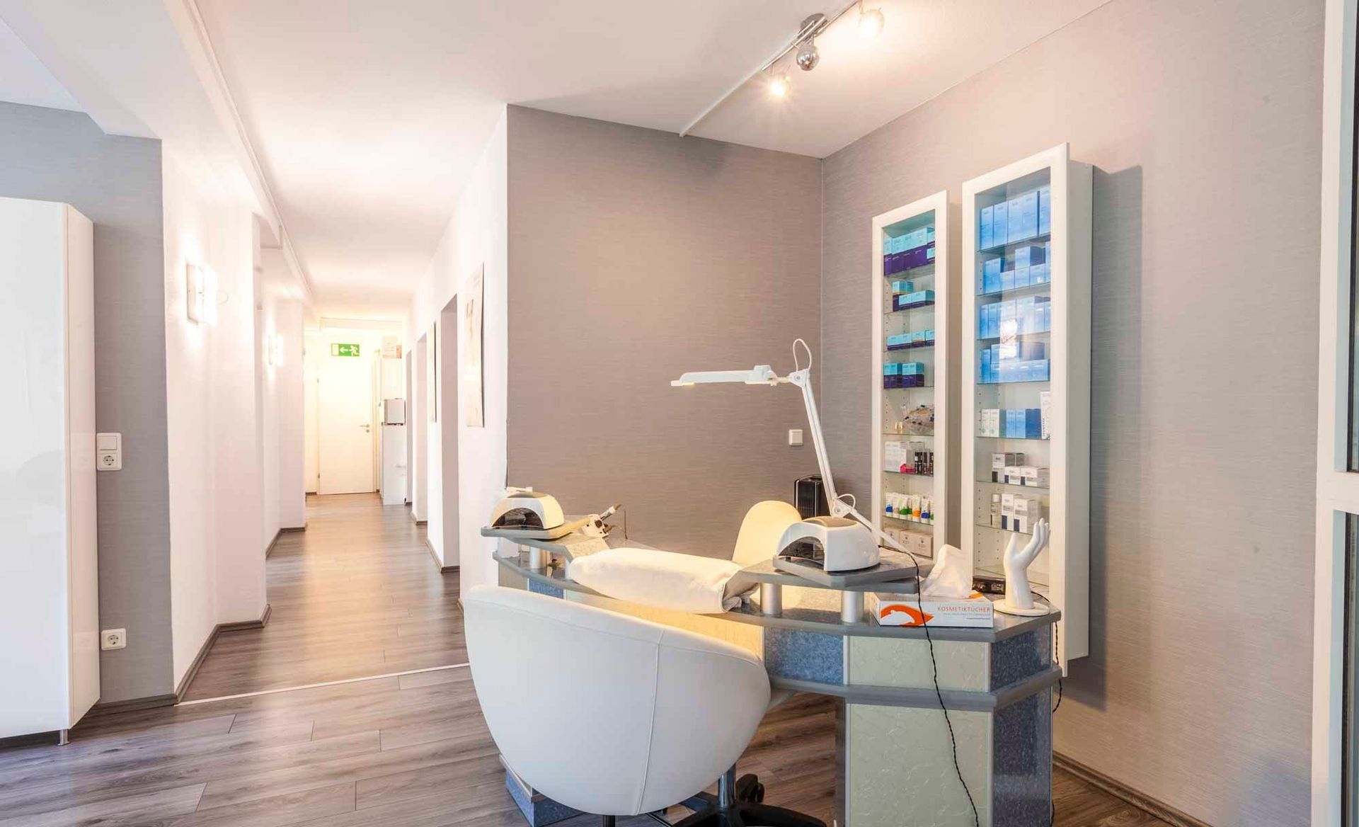 ein Nagelstudio mit einem Stuhl , einem Tisch und einer Lampe .