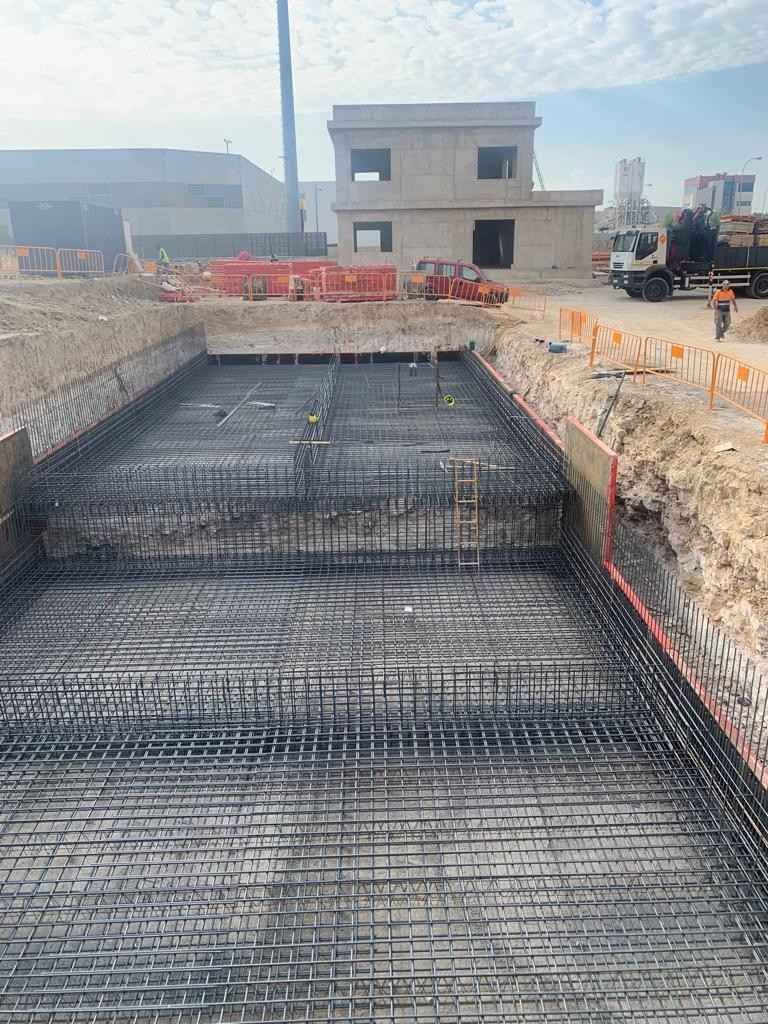 Vertido y nivelación de hormigón en una obra de construcción con la herramienta de un trabajador, con la mezcla gris húmeda en primer plano.