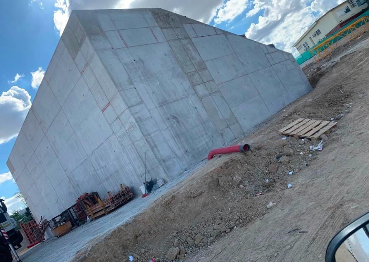 Edificio de gran altura parcialmente construido con una grúa torre contra un cielo azul.