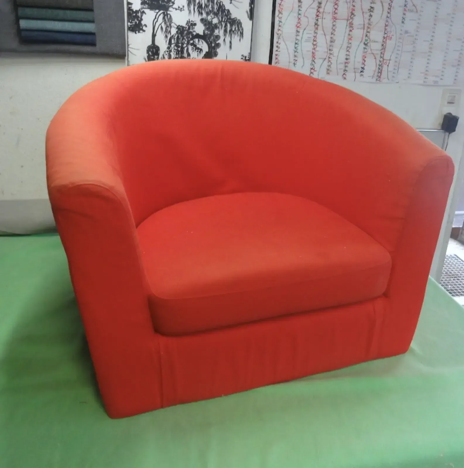 Oranger Polstersessel auf grünem Untergrund.