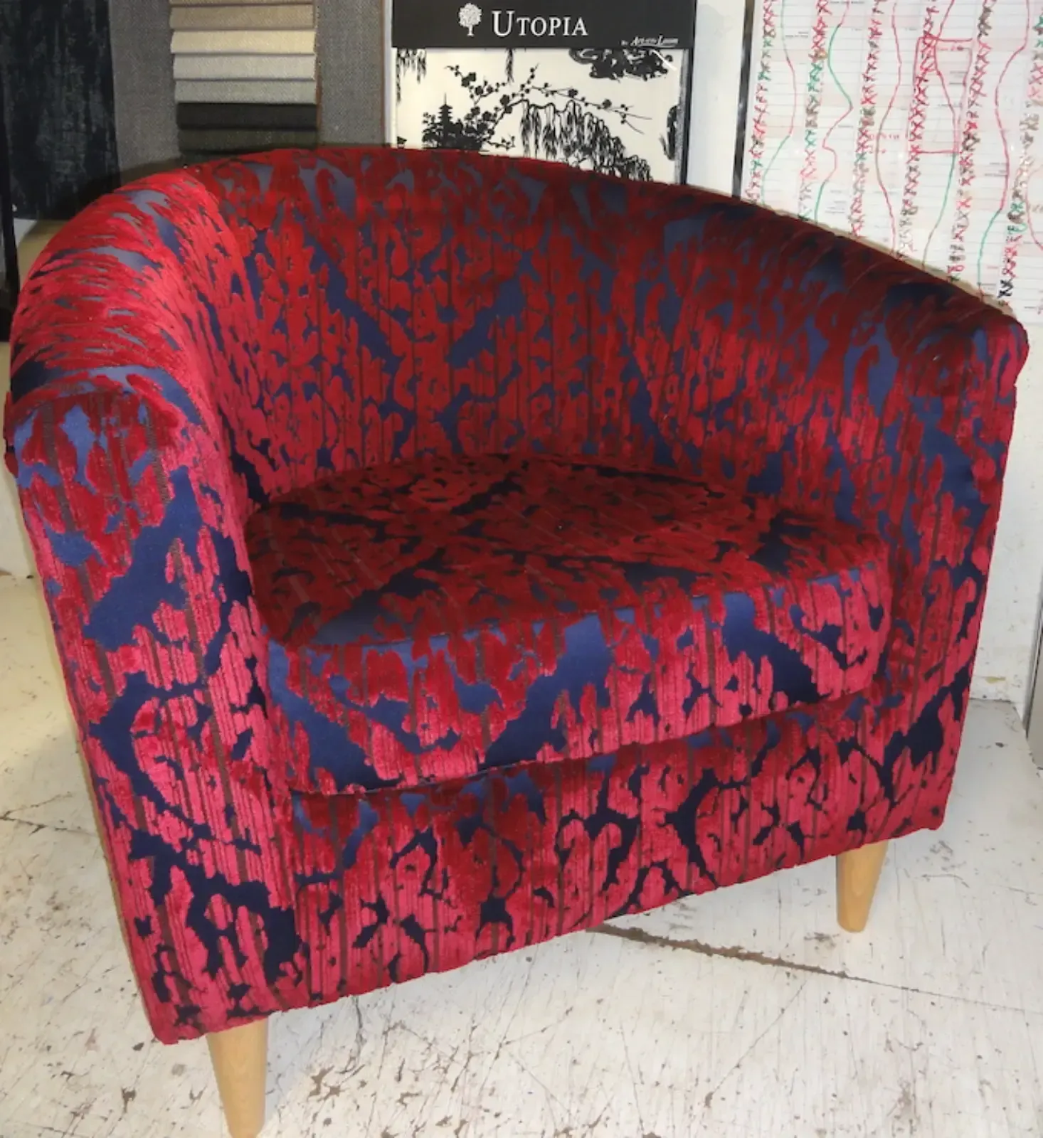 Rot-blau gemusterter Sessel mit hellen Holzbeinen, für den Innenbereich.