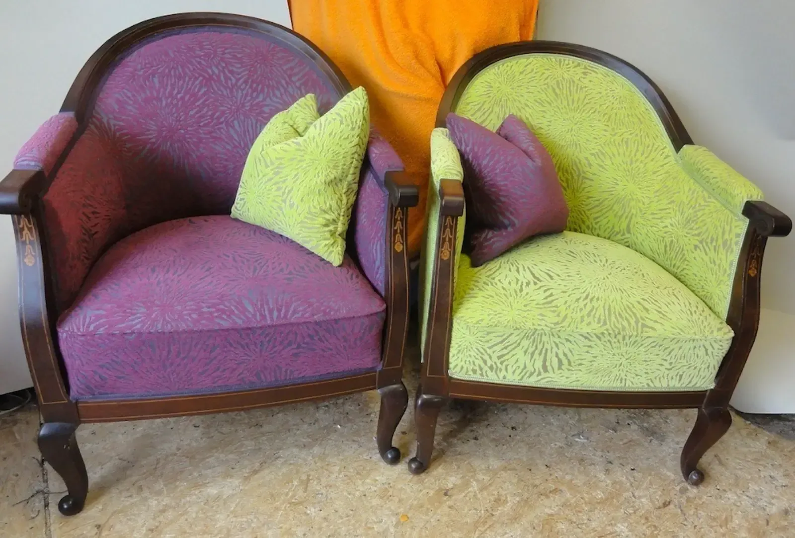 Zwei Sessel mit lila-grünem, strukturiertem Bezug und passenden Kissen. Braune Holzgestelle.