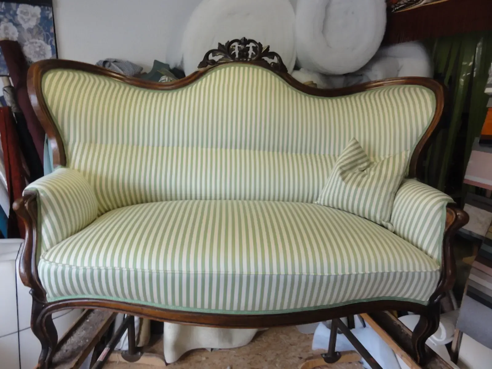 Neu bezogenes, gestreiftes Sofa mit Holzrahmen und dekorativen Details.