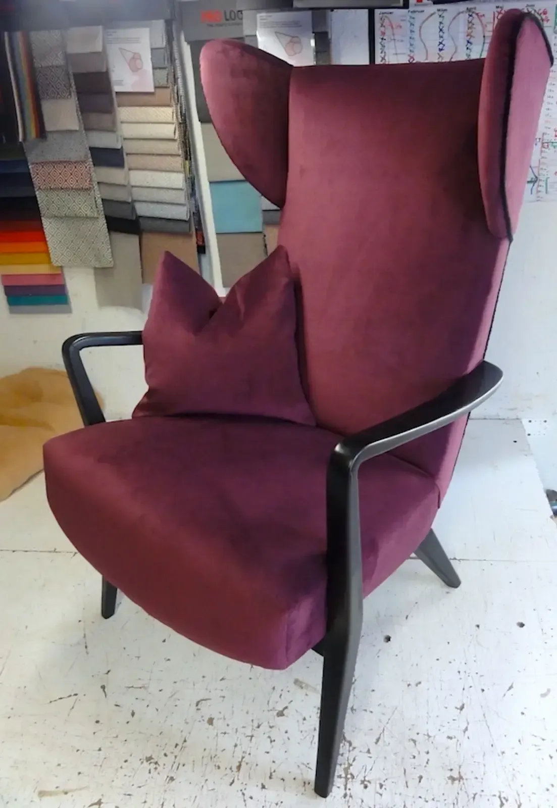 Ohrensessel mit bordeauxrotem Samtbezug und dunklen Holzarmlehnen und -beinen.