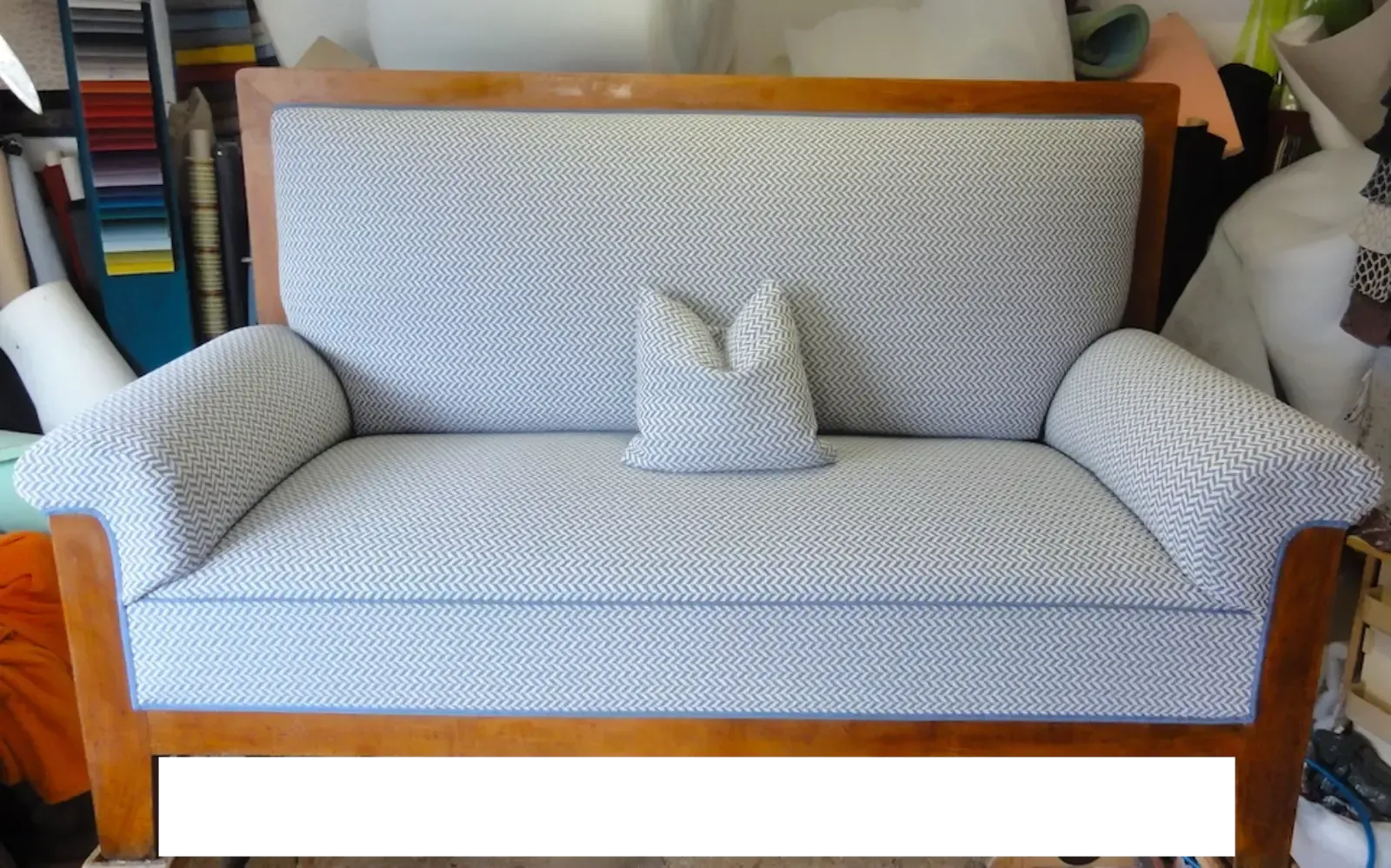 Gepolstertes Zweisitzer-Sofa mit blau-weiß gemustertem Stoffbezug, Holzrahmen und passendem Kissen.