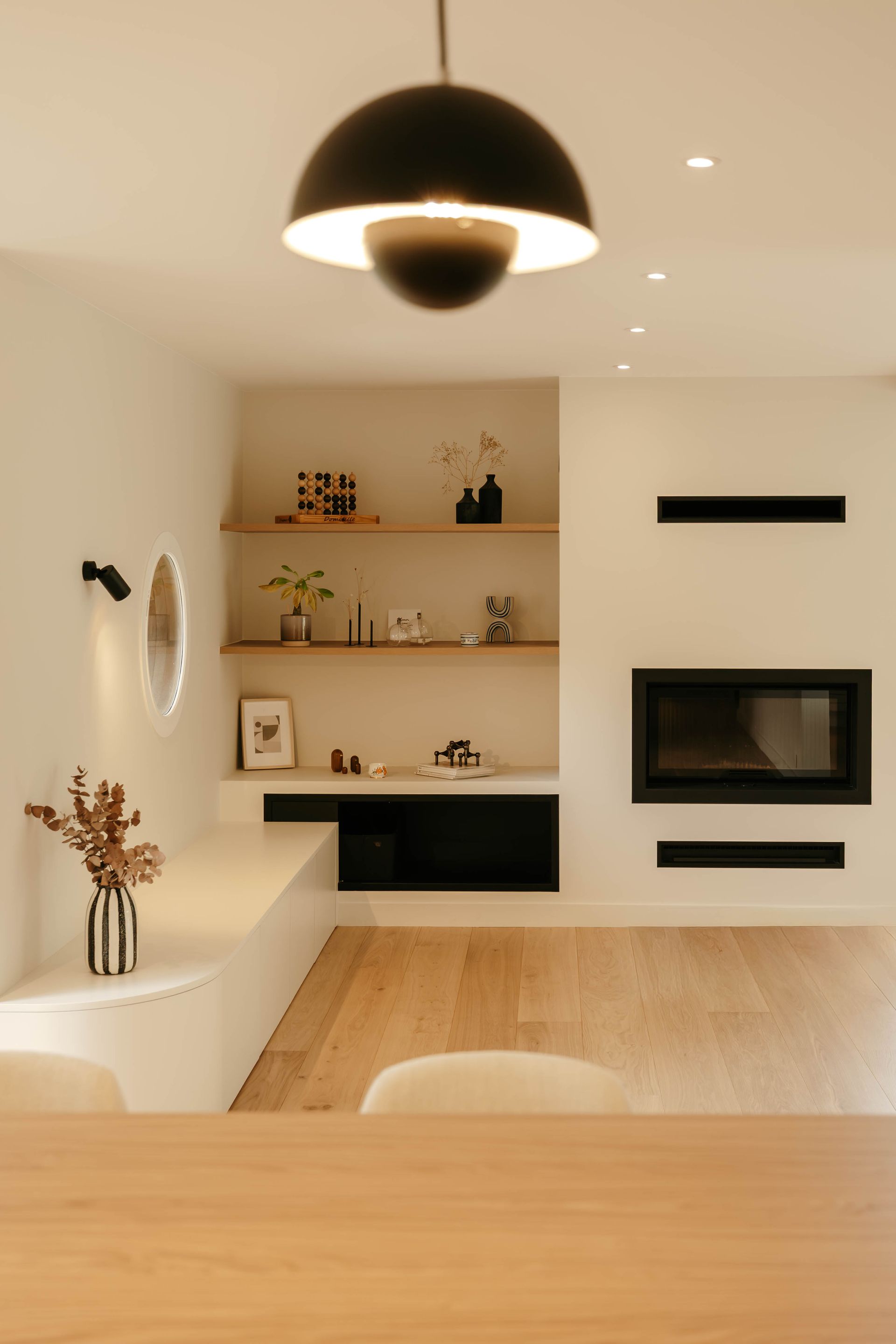 Salon moderne avec étagères intégrées, cheminée, suspension et table à manger en bois