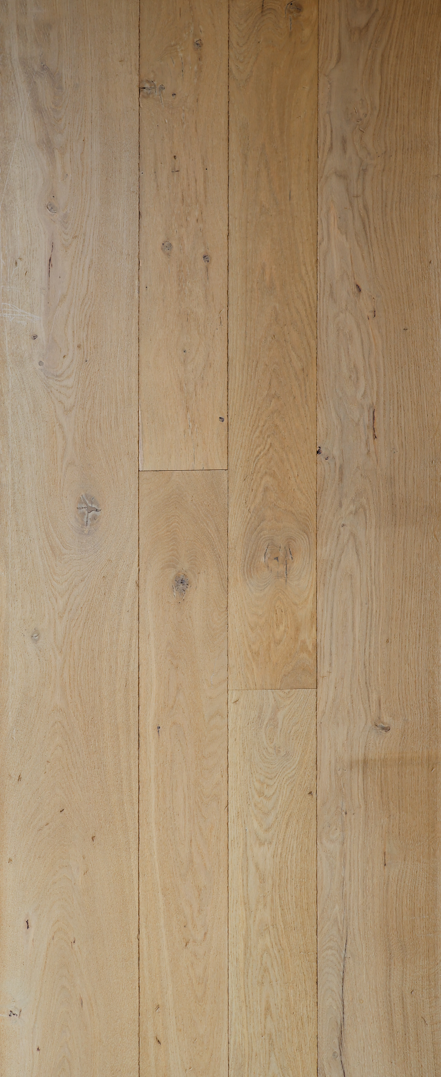 Des lames de parquet clair, avec leur veinage naturel et leurs joints visibles sur toute l’image