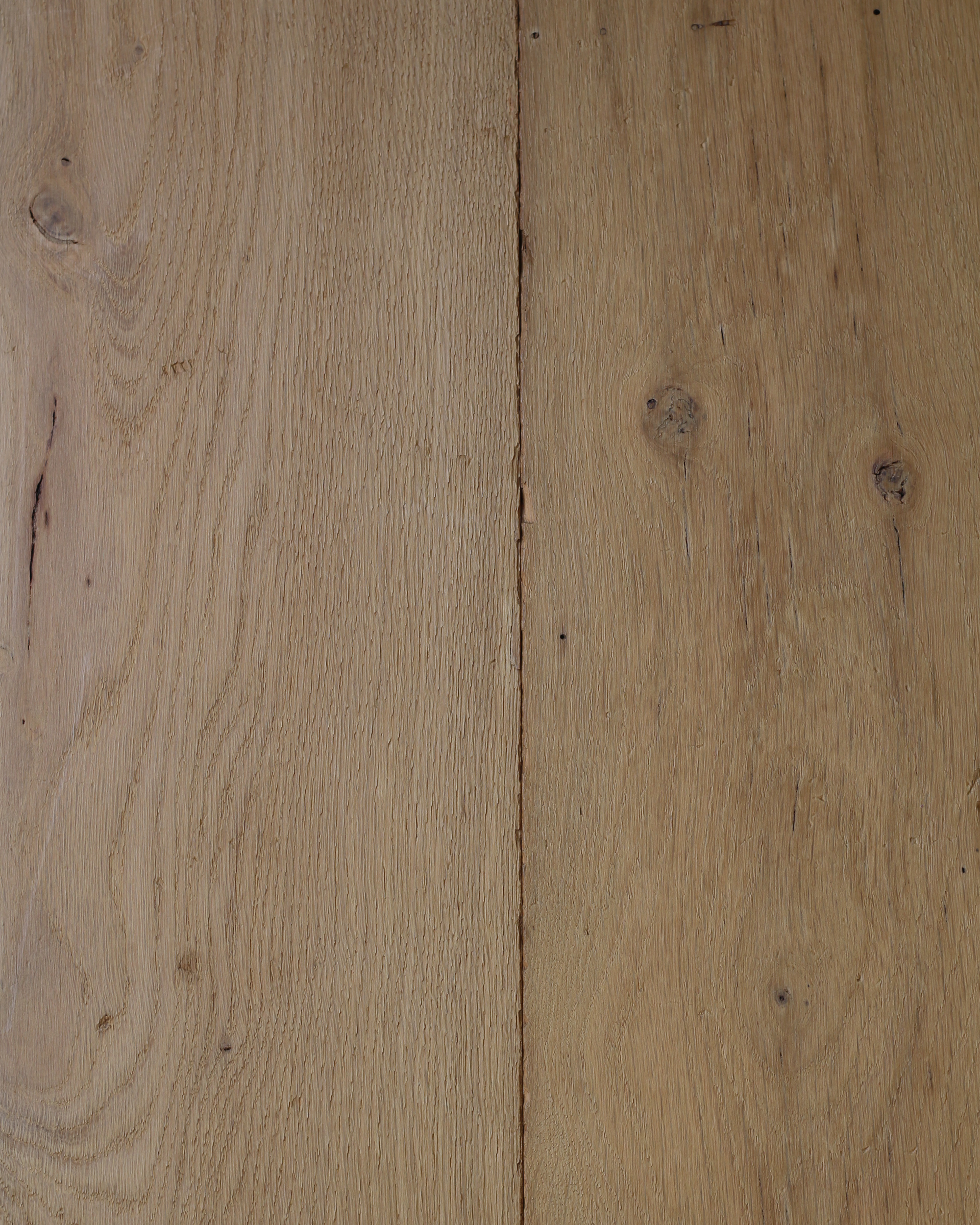 Des lames de parquet clair, avec leur veinage naturel et leurs joints visibles sur toute l’image