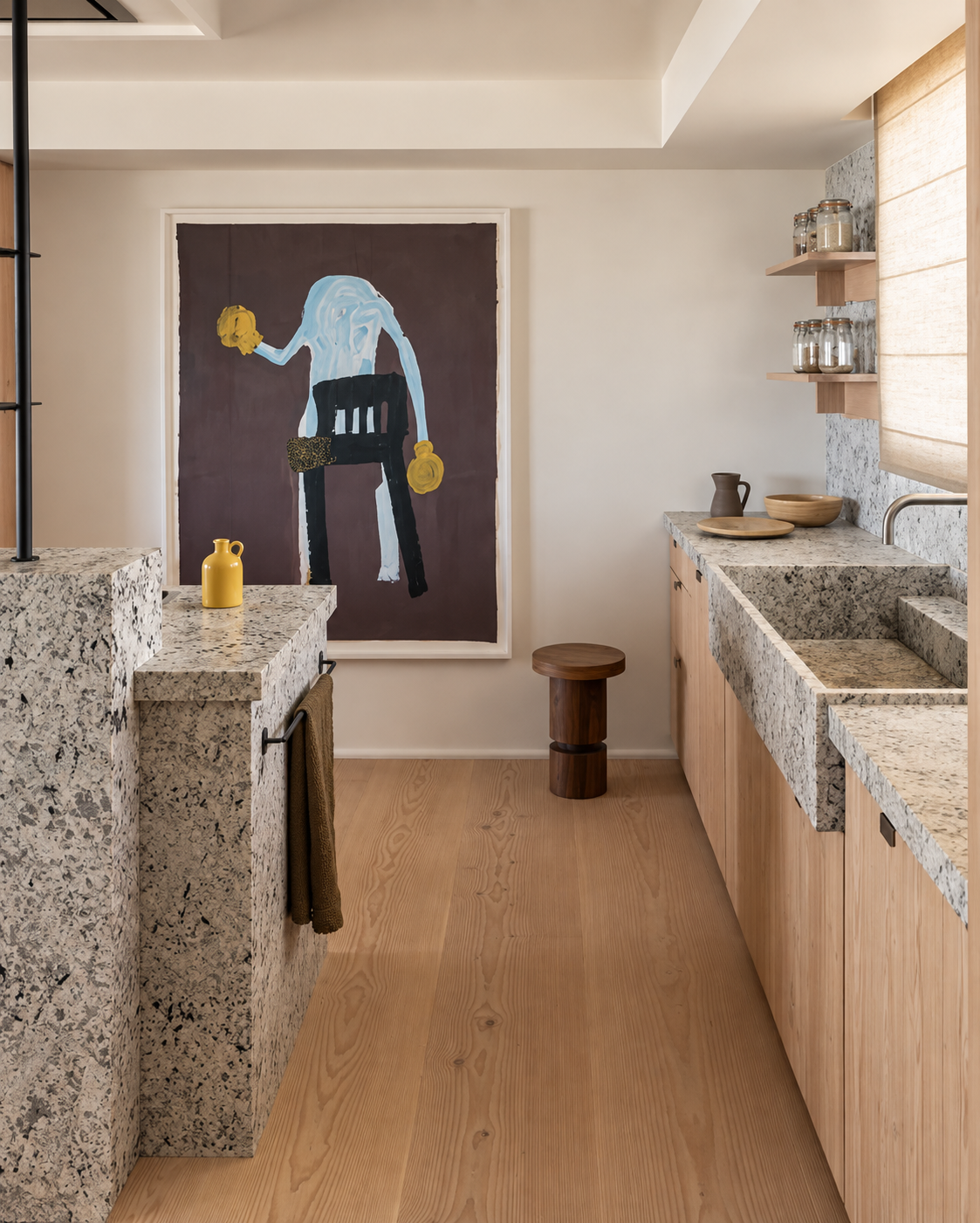 Cuisine moderne avec des comptoirs mouchetés, des placards en bois et un tableau encadré sur le mur du fond.