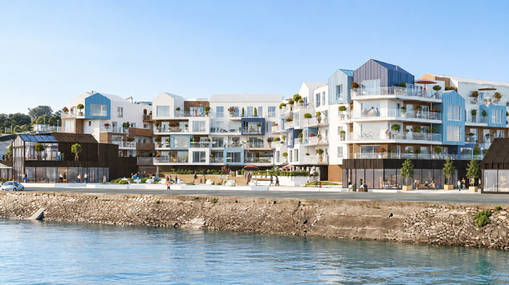 Des immeubles d’habitation en bord de mer le long d’un littoral rocheux, sous un ciel bleu dégagé.
