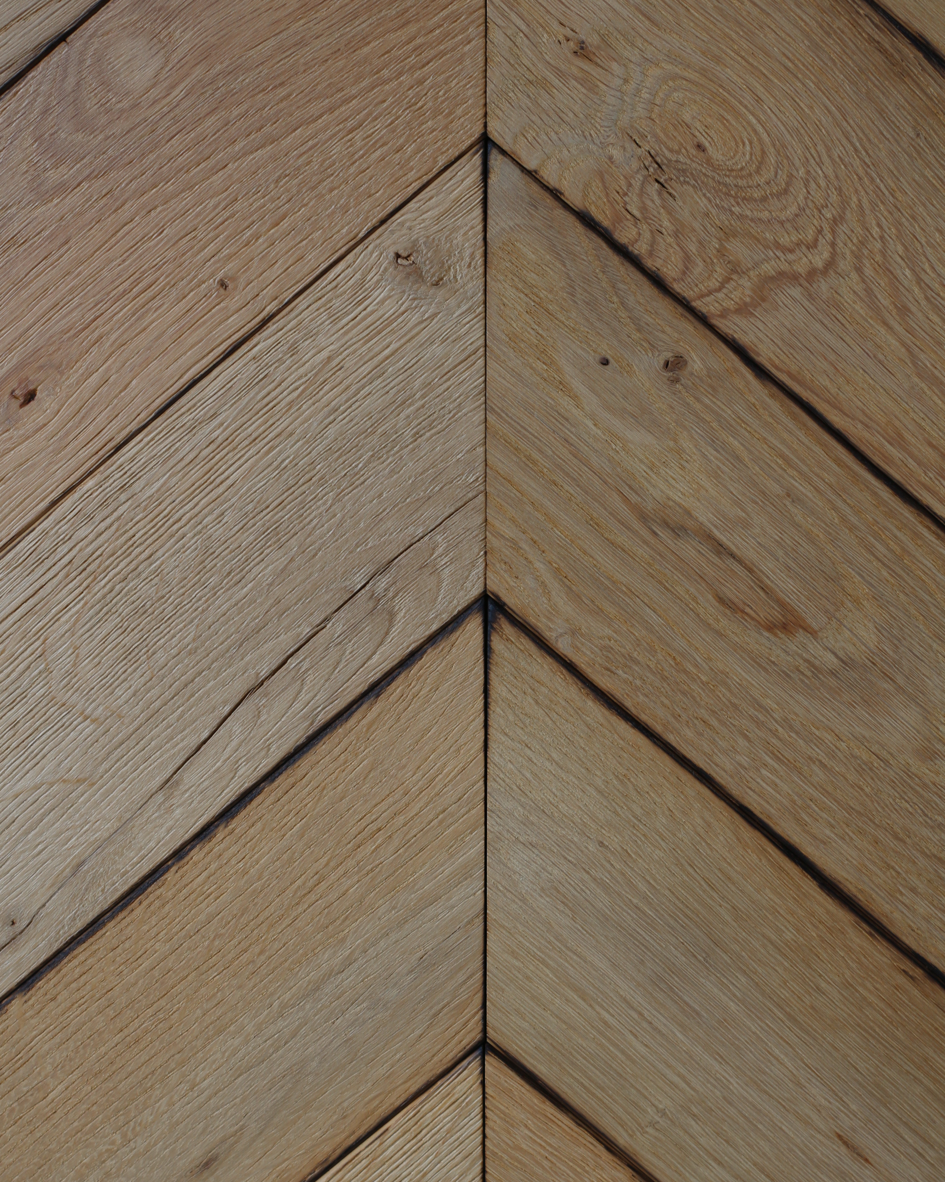 Des lames de bois clair à motif chevron se rejoignent dans un angle, formant une jointure en V.