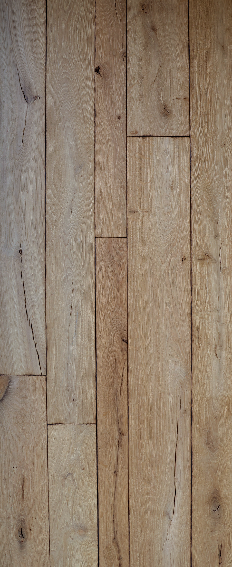 Planches de parquet verticales en bois, dans des tons brun clair, avec un grain et des joints bien visibles