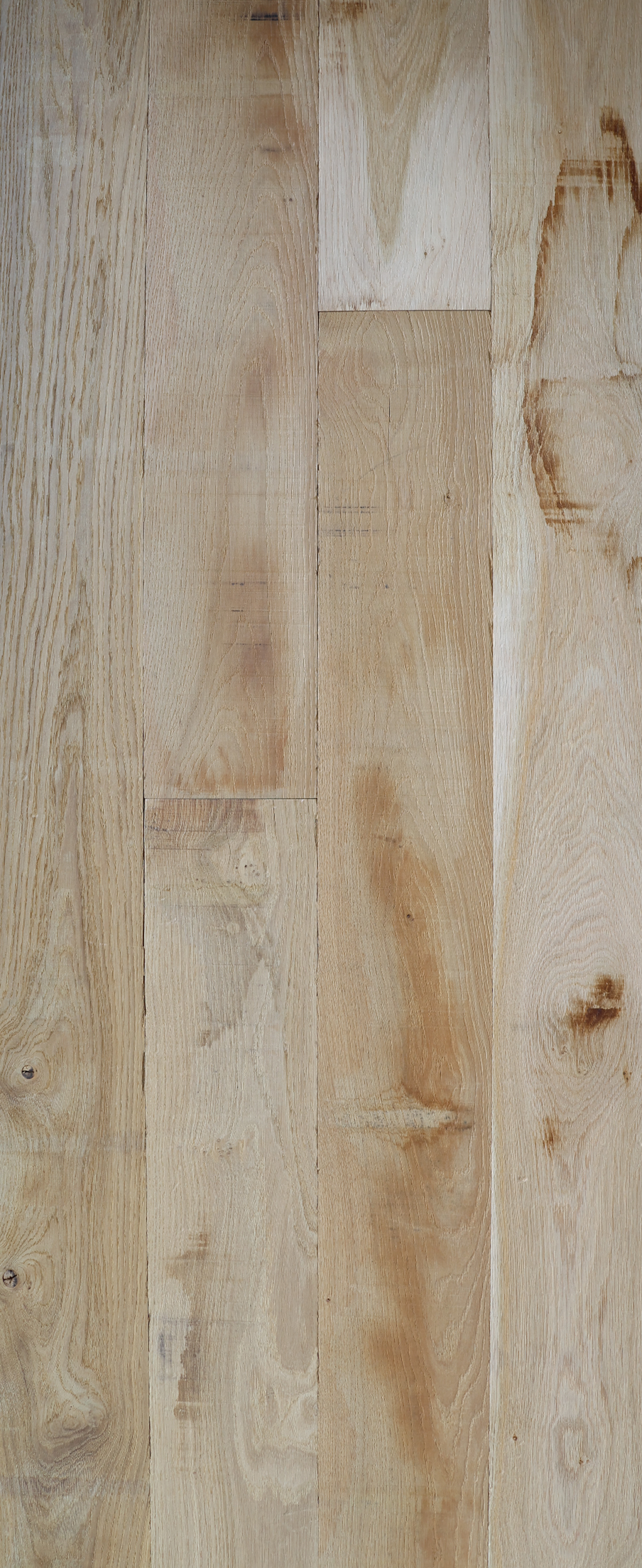 Gros plan sur des planches de bois brun clair patinées, avec leurs nœuds et leurs veines.