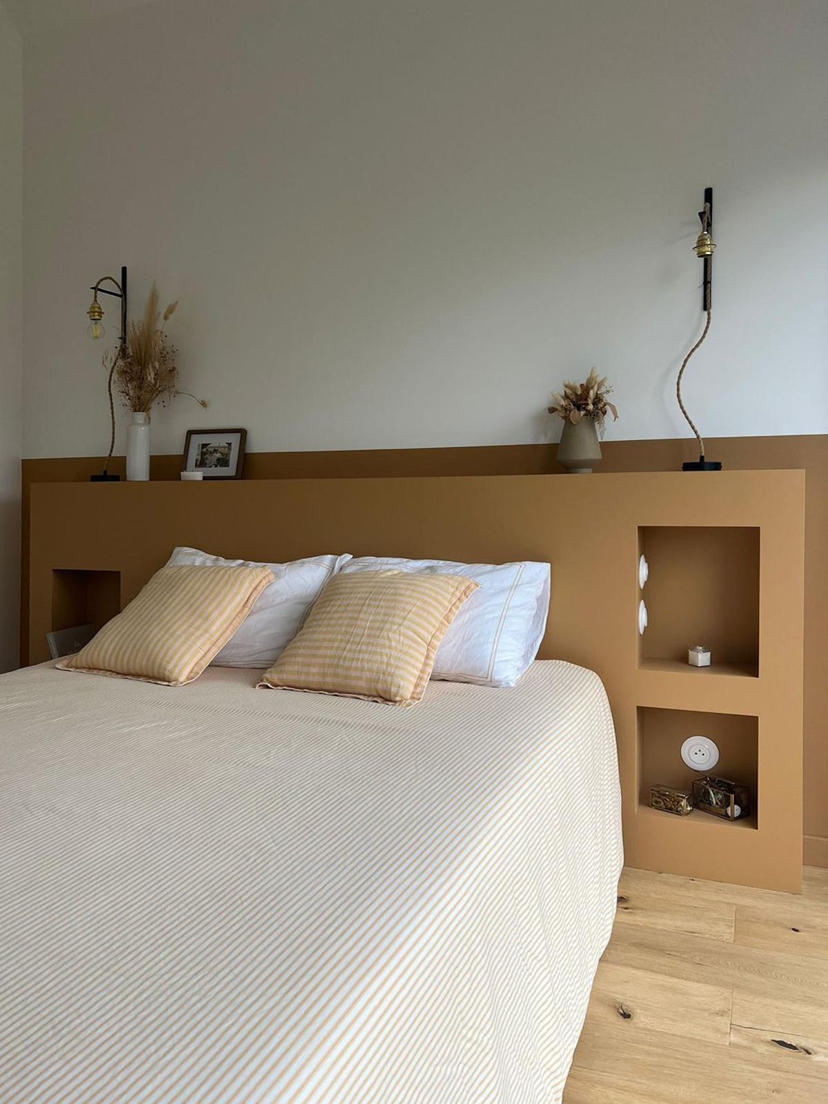 Chambre minimaliste avec un lit beige, du linge de lit blanc
