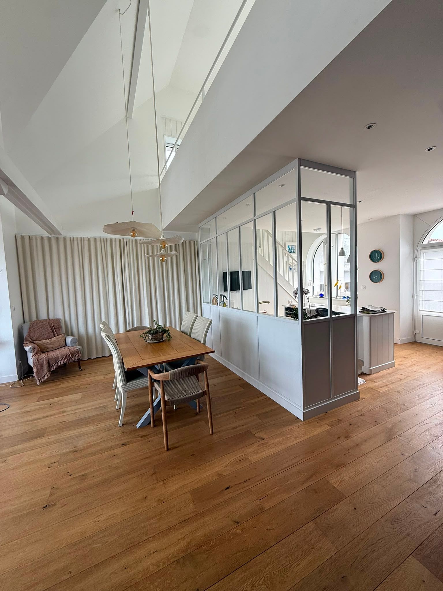 Salon-salle à manger moderne et ouvert, avec parquet, cloison vitrée, table à manger et rideaux à rayures