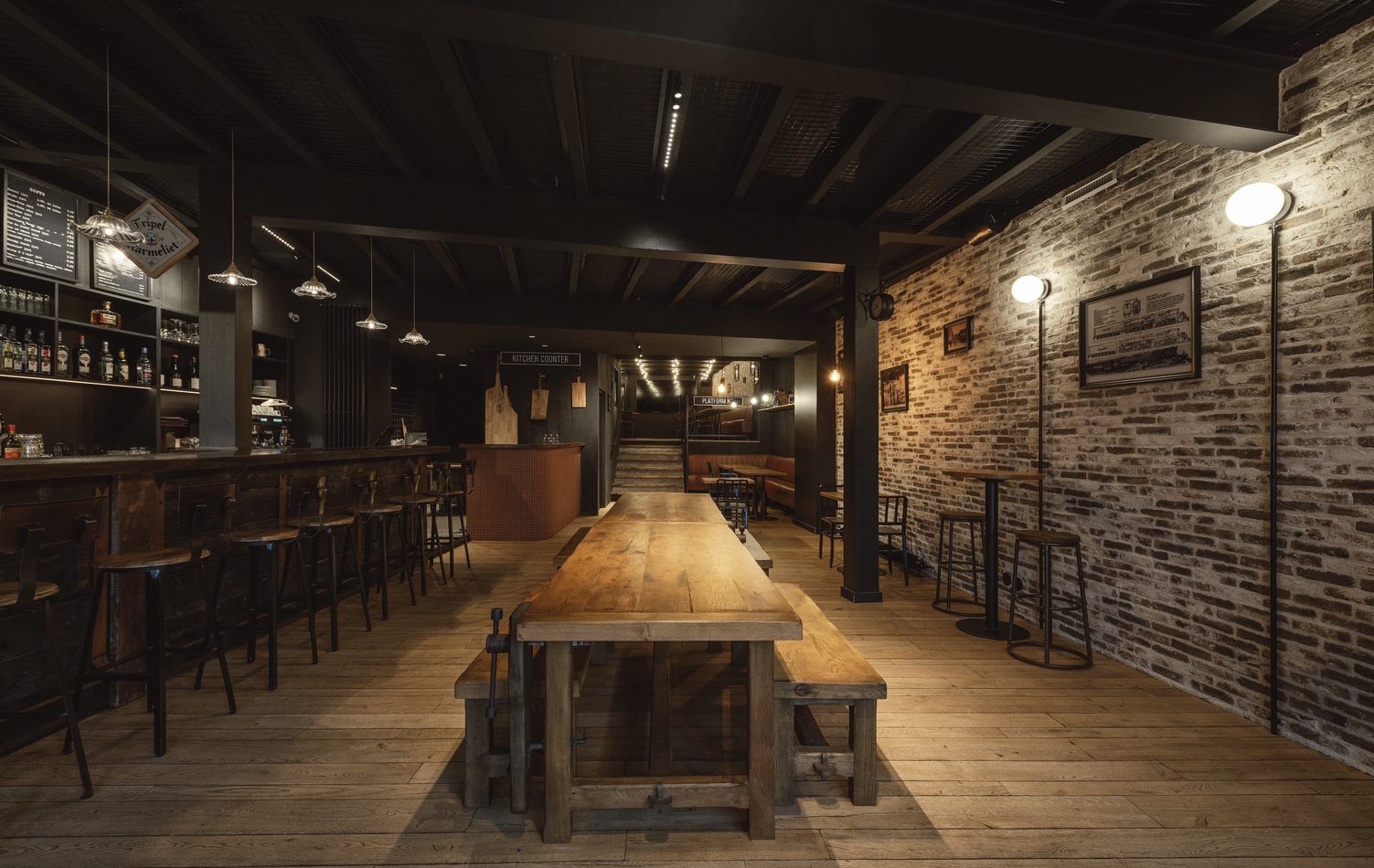 Intérieur rustique de bar vide avec de longues tables en bois, des tabourets, des murs en pierre et un éclairage chaleureux