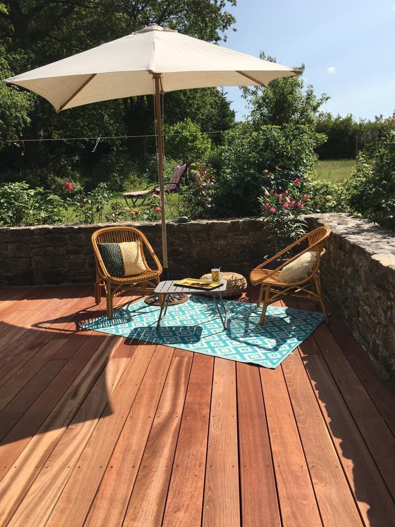 Espace repas sur une terrasse avec deux fauteuils en osier, une petite table