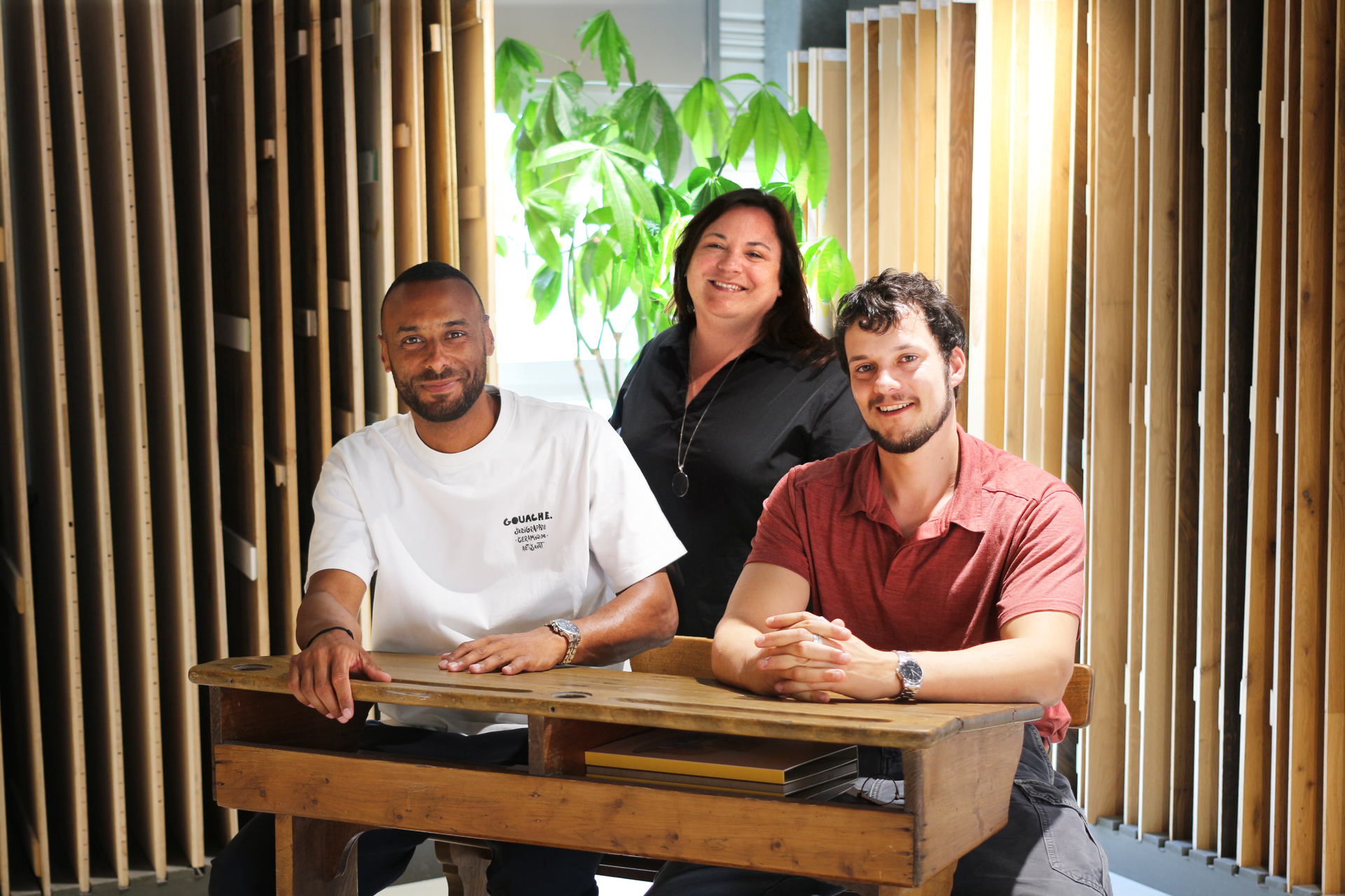 Trois personnes souriantes derrière une table en bois