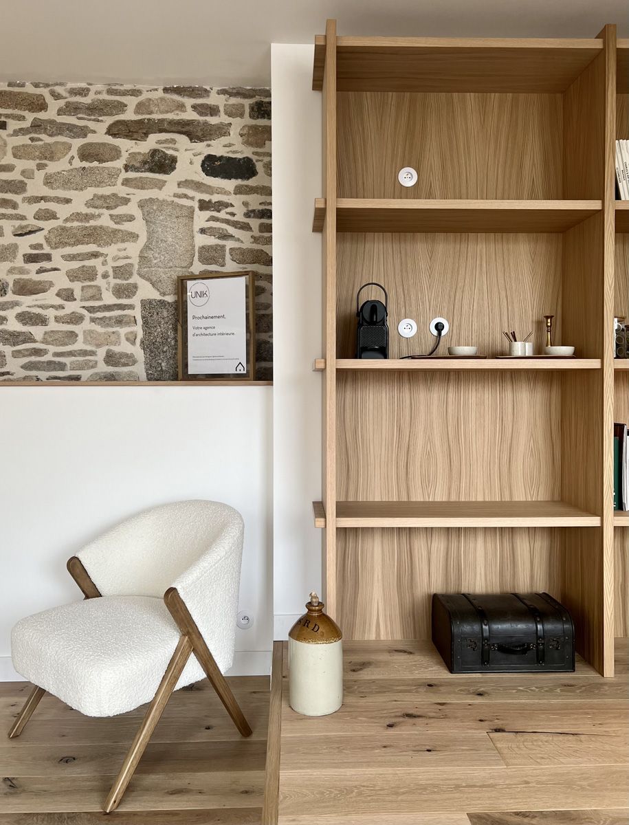 Pièce chaleureuse avec un mur en pierre, une chaise blanche