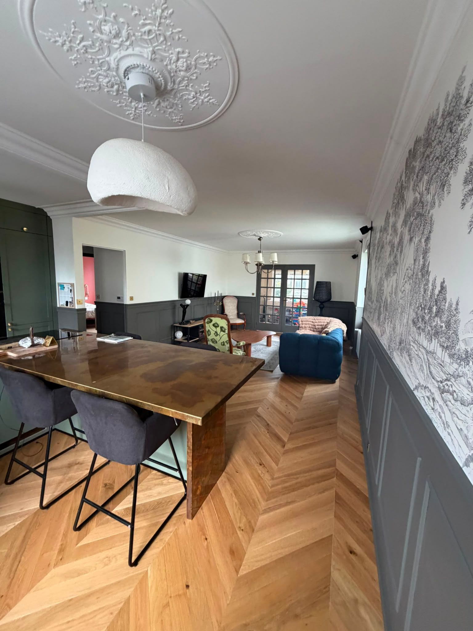 Salle à manger et salon modernes à aire ouverte, avec une table en bois, un parquet à chevrons et du papier peint à motifs