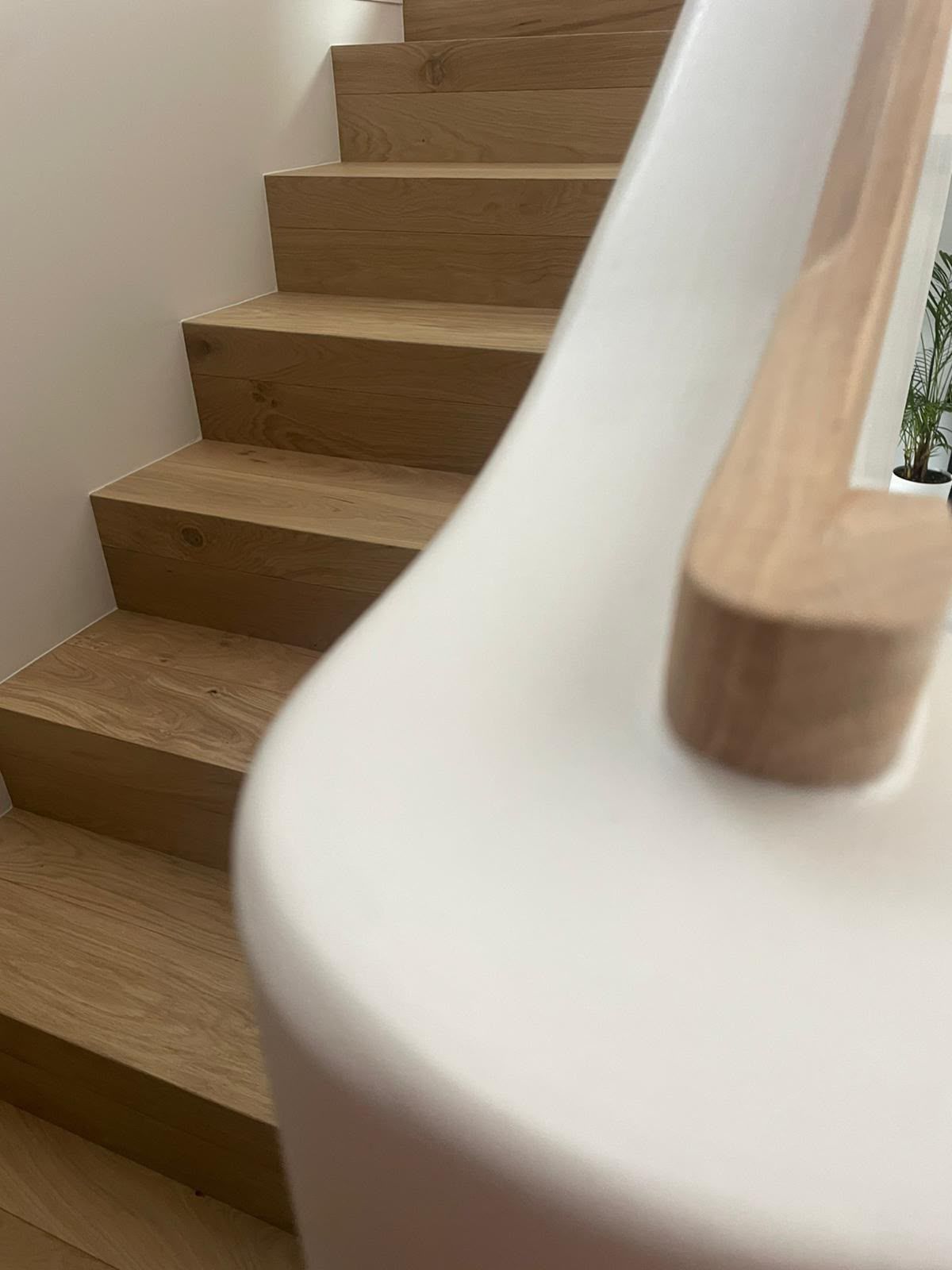 Escalier en bois avec une rampe blanche incurvée dans un intérieur lumineux