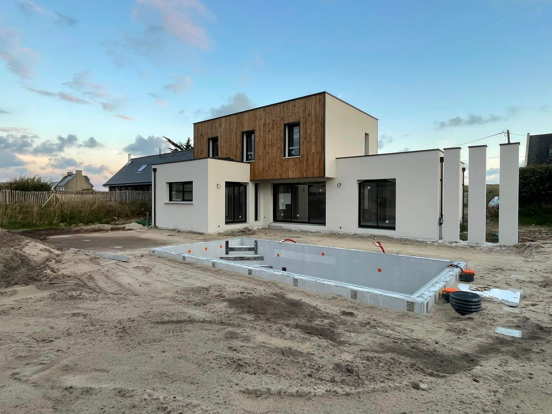 Maison moderne à deux étages en construction, avec un jardin et une piscine à l’avant encore à aménager