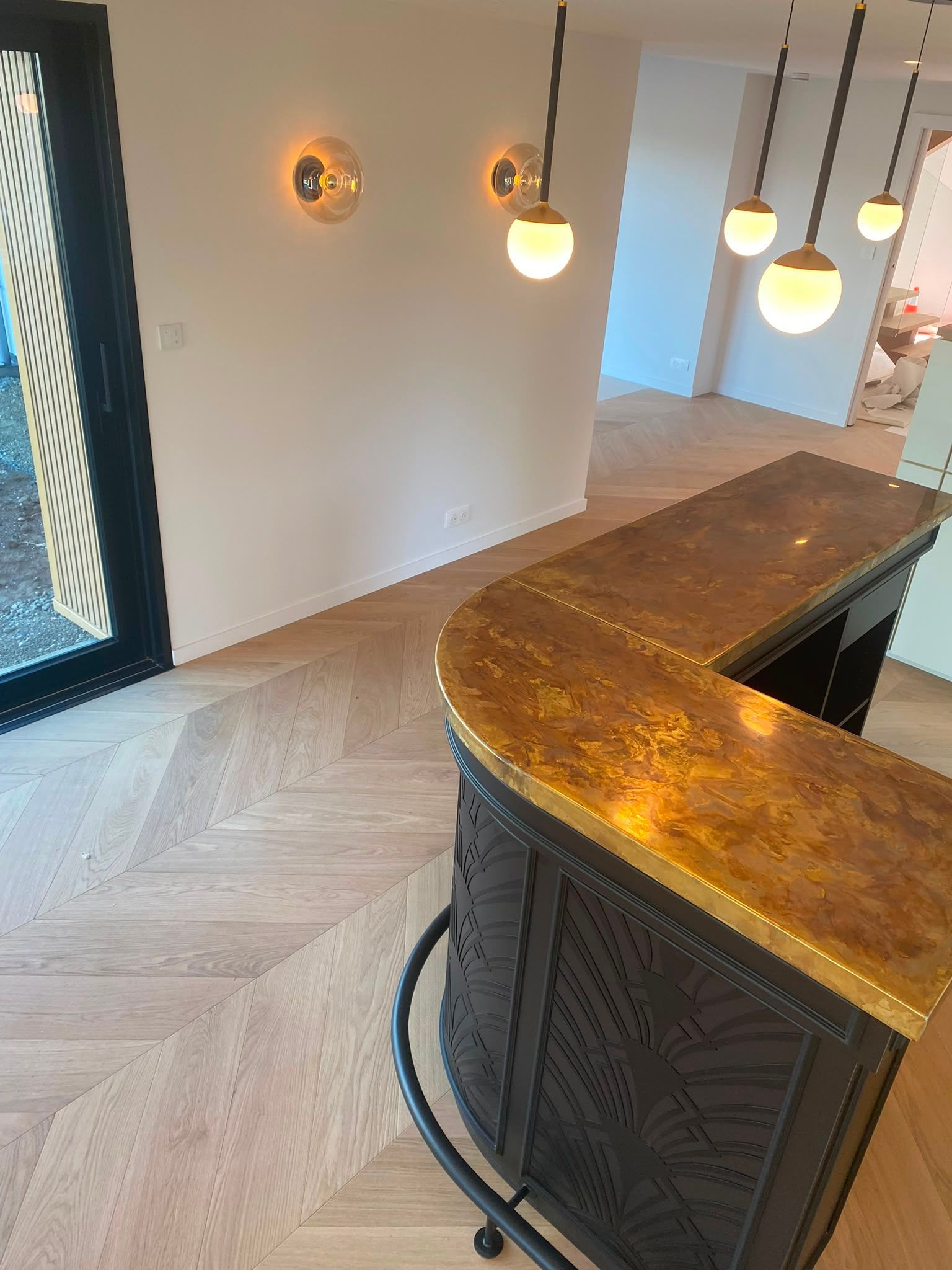 Bar en bois incurvé avec des suspensions et un parquet à chevrons dans un intérieur moderne