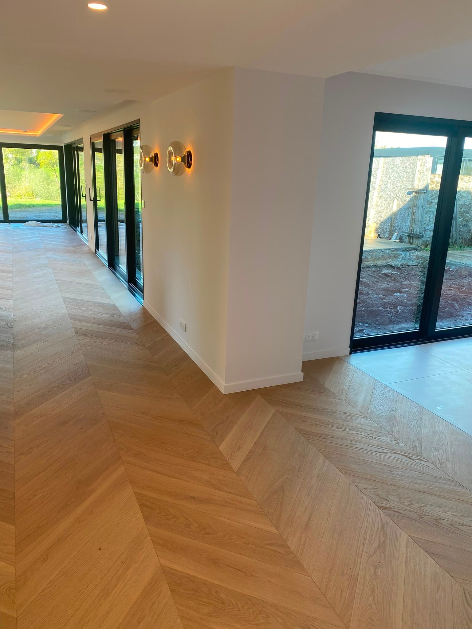 Couloir lumineux et vide avec un parquet à chevrons