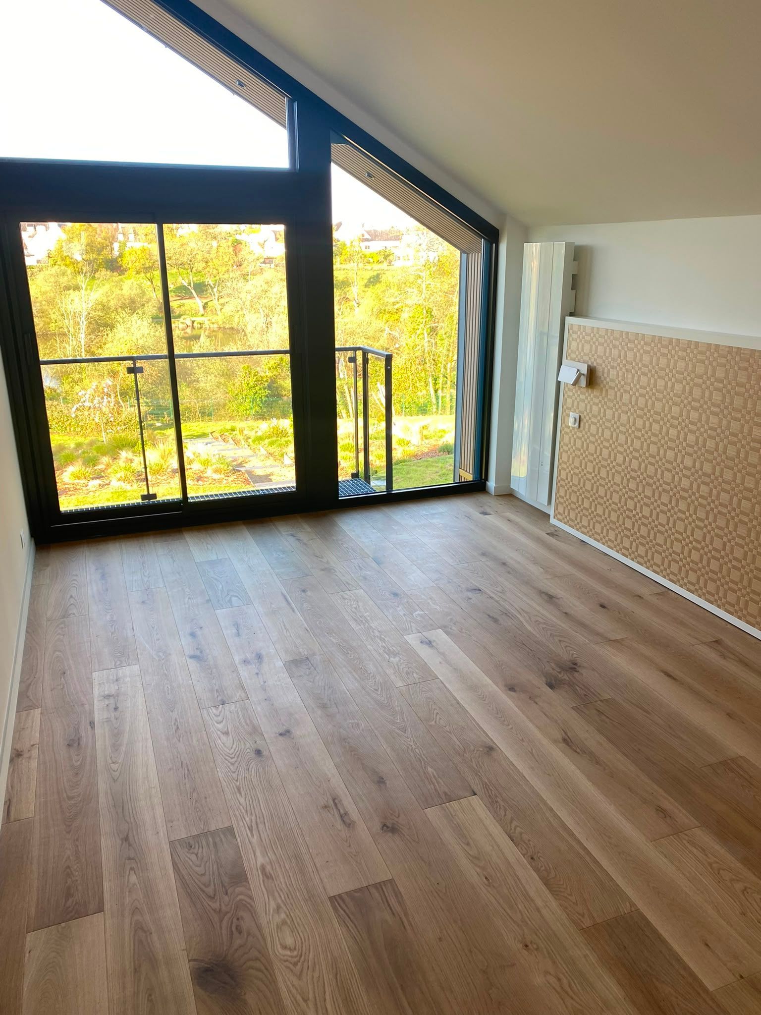 Pièce mansardée vide avec un plafond en pente, un parquet et de grandes fenêtres