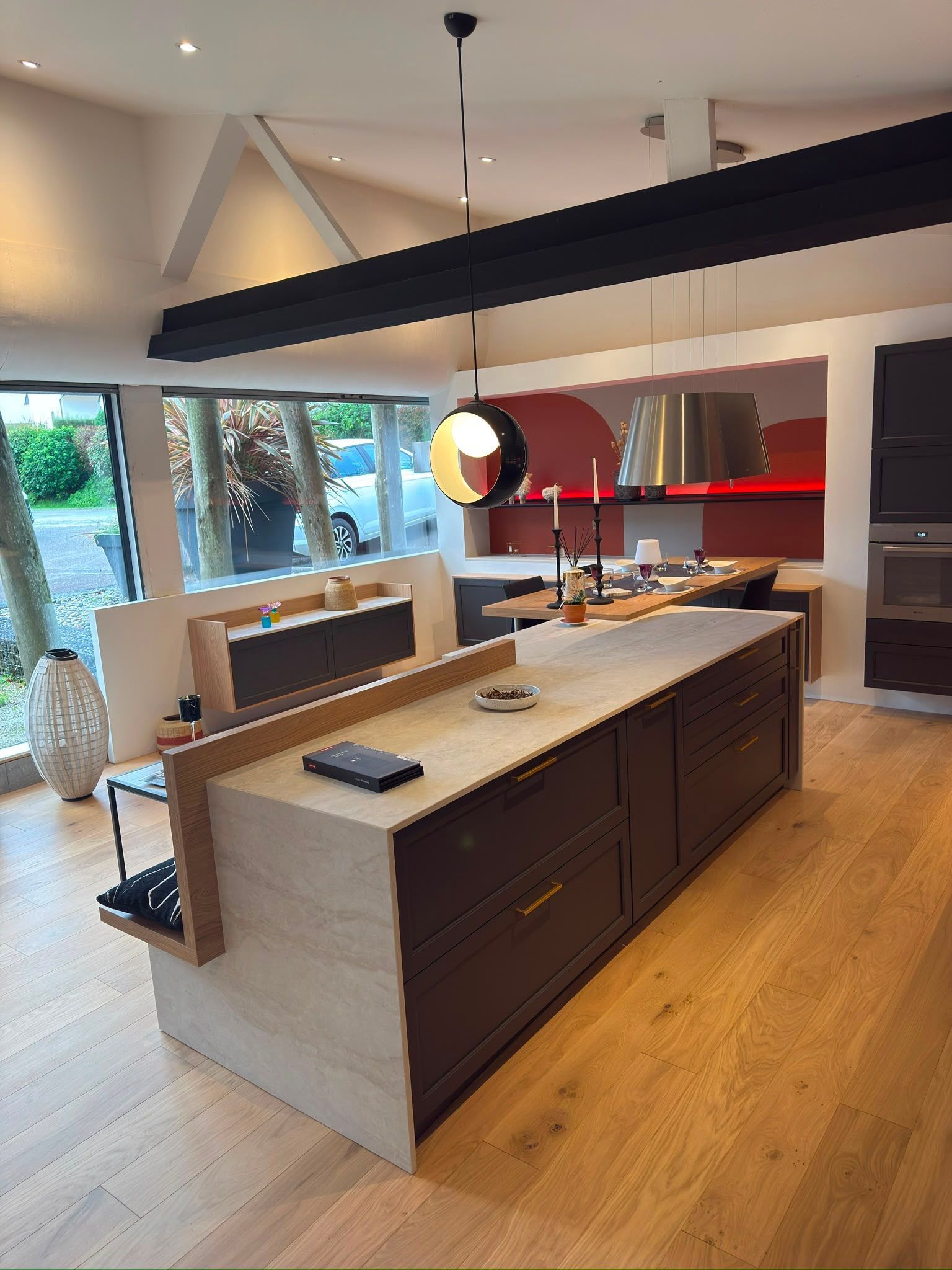 Cuisine moderne avec îlot foncé, parquet clair, crédence rouge et grandes fenêtres
