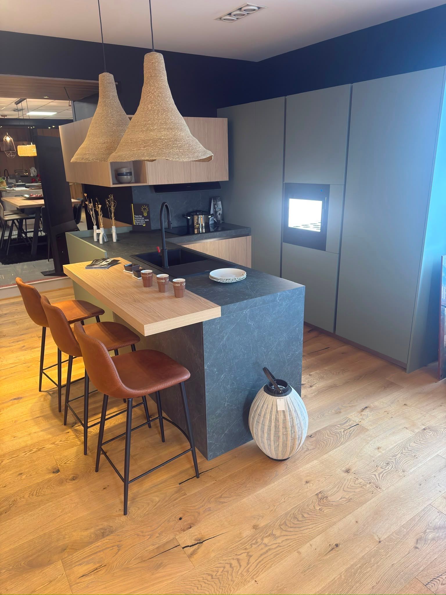 Cuisine moderne avec îlot central, suspensions tressées, tabourets en bois et meubles bleus