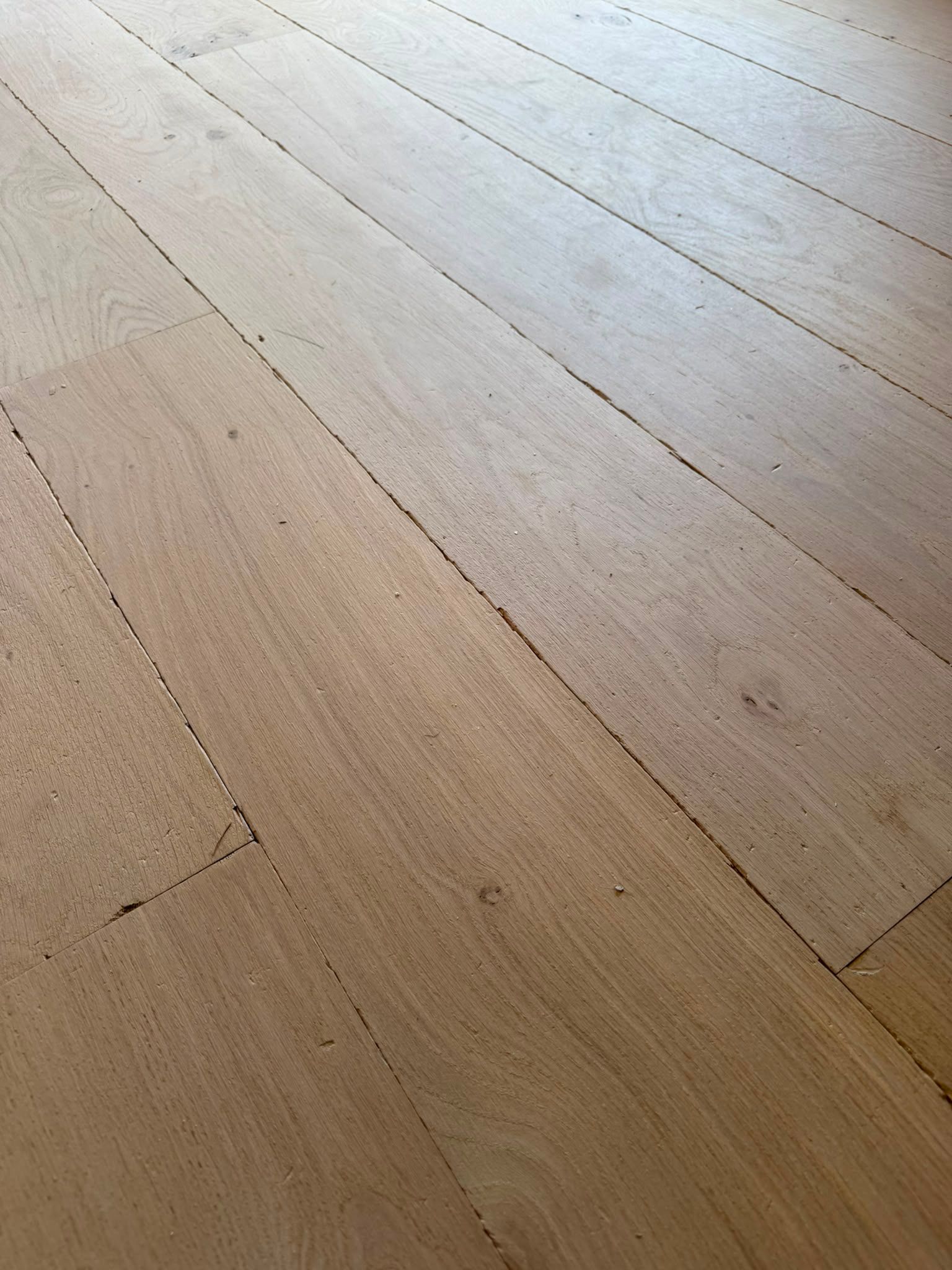 Des lames de parquet en bois clair, avec des joints visibles et un veinage discret.