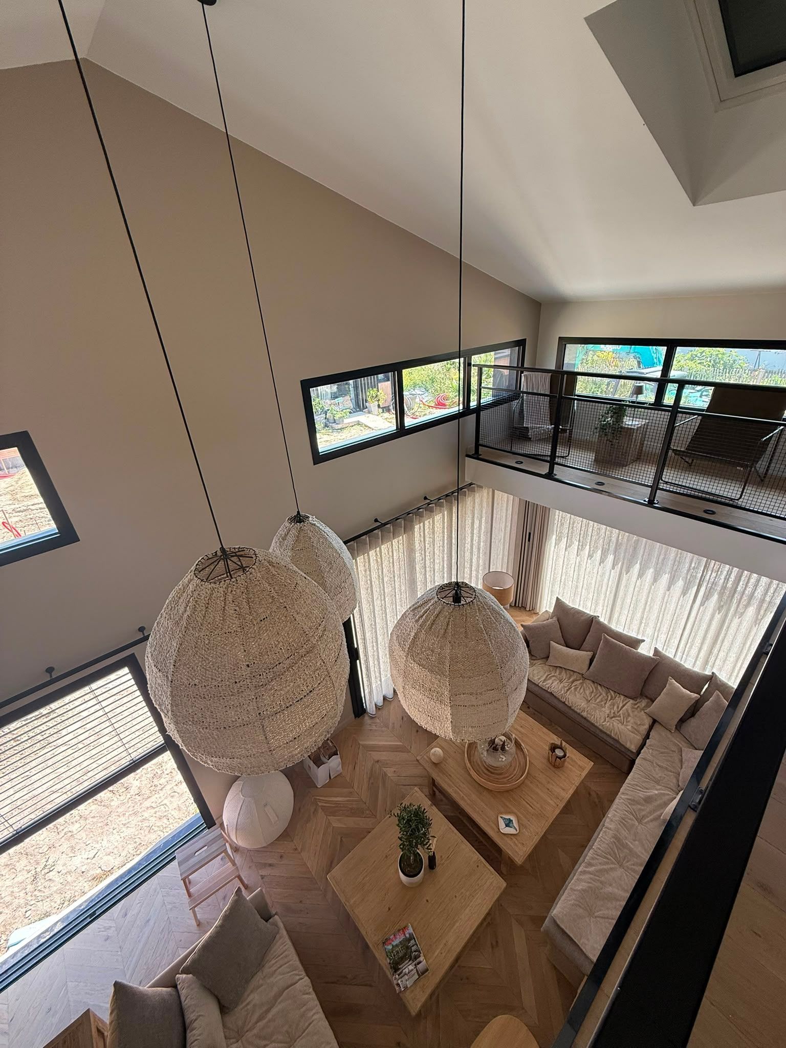 Salle à manger avec un haut plafond, deux suspensions, une table en bois 