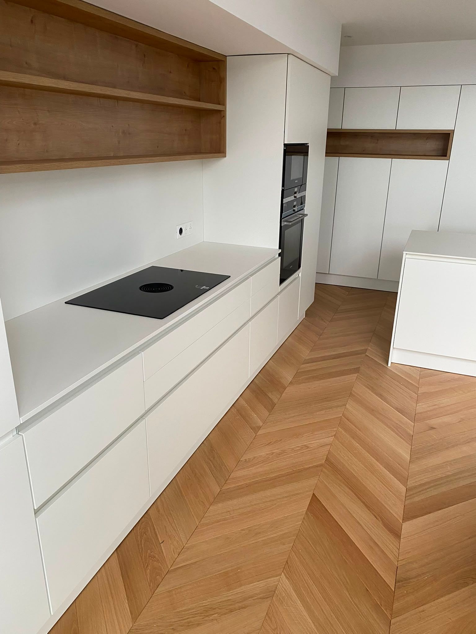 Cuisine moderne et minimaliste avec des placards blancs, des étagères en bois et un parquet à chevrons en bois