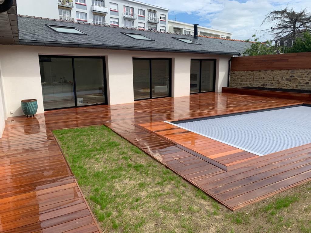 Terrasse en bois avec une piscine couverte, attenante à une maison moderne dotée de baies vitrées coulissantes